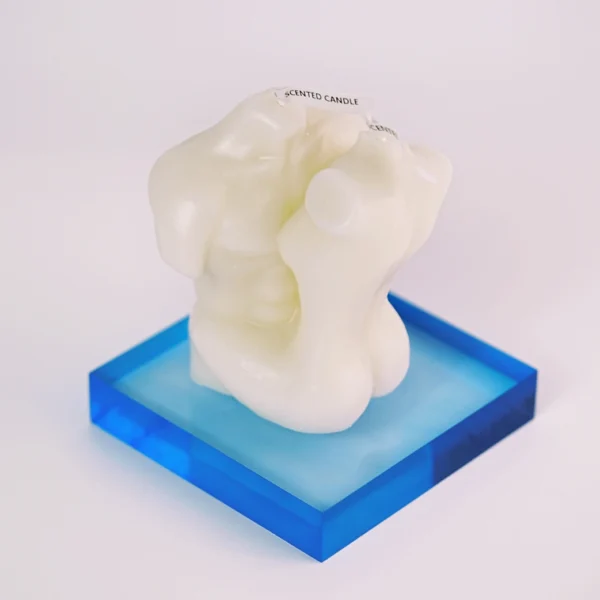 A unique sculptural candle featuring a stylized representation of two intertwined torsos in a creamy white color. The candle is placed on a striking blue acrylic base, creating a captivating contrast with its curvy, soft shapes. The top of the candle features a label reading "Scented Candle," hinting at its aromatic qualities. This artistic piece effortlessly combines functionality with aesthetics, making it an ideal choice for setting the mood in any romantic space, embodying the essence of sensual candles. The overall design radiates elegance and intimacy, perfect for enhancing a cozy atmosphere.