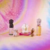 A vibrant display featuring five artistic aromatherapy candles shaped like the upper and lower torsos of human figures, each resting on colorful, translucent stands. The candles range in hues from deep brown to soft white, capturing a variety of skin tones. The background is a dreamy blend of pastel colors, creating an ethereal ambiance. These unique, sculptural candles not only serve as eye-catching decor but also evoke a sense of warmth and intimacy, making them ideal for creating a cozy atmosphere with sensual candles. The entire composition radiates a feeling of artistic elegance, perfect for enhancing any romantic setting.