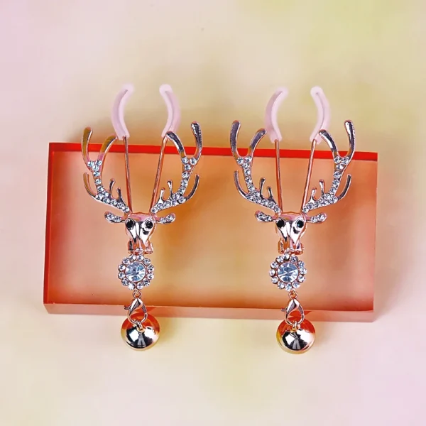 A pair of stylish nipple clamps is displayed against a soft pastel background. The clamps feature ornate deer skull designs with antlers, embellished with sparkling rhinestones. Below the skull, a shiny metallic ball dangles from each clamp, adding an eye-catching detail. The pink rubber tips ensure comfort, making these nipple clamps both visually striking and beginner-friendly for those exploring role play dynamics.