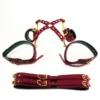 A stylish set of bed restraints set featuring a luxurious burgundy harness made from soft, high-quality leather. The harness is designed with adjustable straps, gold metal buckles, and elegant detailing, creating a refined look. Attached to the harness are matching wrist cuffs, showcasing the same rich color and gold accents. Below, a set of connecting straps lies flat, highlighting their sturdy construction and functionality. Displayed against a clean white background, this eye-catching ensemble combines elegance with playfulness, making it a striking addition for those exploring bed restraints set in an intimate setting.