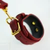 An elegant set of bed restraints set showcasing a deep burgundy leather harness and wrist cuffs. The harness features a crisscross design with decorative gold hardware and adjustable straps, providing both style and functionality. The wrist cuffs are lined with soft black padding for comfort and are secured with gold buckles, ensuring a snug fit. Laid out against a clean white background, the entire ensemble radiates sophistication, making it a striking piece of bed restraints set for those looking to explore their intimate experiences with a blend of luxury and playfulness.