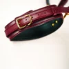 A close-up view of a luxurious burgundy leather collar designed for bed restraints, featuring a smooth, glossy finish. The collar is secured with a gold metal buckle and ring, allowing for easy adjustment and a secure fit. Subtle stitching details run along the edges, adding an elegant touch to the design. The inside of the collar is lined with a soft black material, enhancing comfort. Displayed on a light background, this stylish piece exemplifies sophisticated bed restraints set, perfect for those looking to explore intimacy with a blend of functionality and aesthetics.