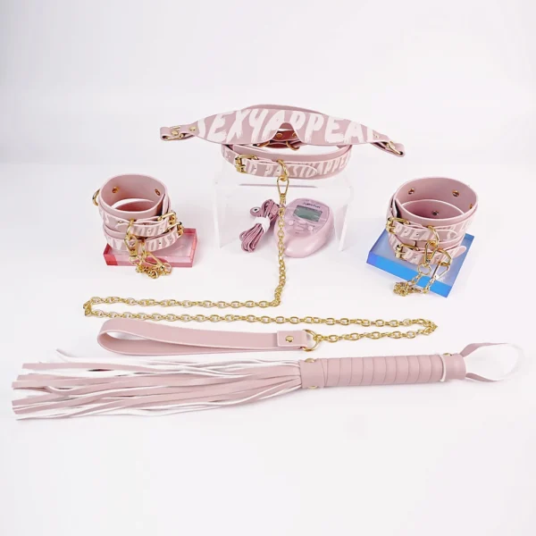 A stylish pink electro-stimulation bed restraints set arranged on a clean white background. The set includes a padded harness and multiple cuffs, all featuring bold text that reads "SEXY APPAREL" in a playful font. Gold metal accents and chains enhance the luxurious appeal of the gear. A sleek pink control unit is positioned nearby, indicating its function for the electro-stimulation features. At the forefront, a soft leather flogger with long, delicate strands showcases elegant craftsmanship. This vibrant collection of bed restraints set offers a modern and playful take on intimate exploration, perfect for adventurous experiences.