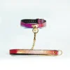 A vibrant restraint collar featuring a stunning gradient design that transitions from deep pink to shimmering gold. The collar is made of textured leather, elegantly showcasing a unique snakeskin pattern. It is secured with a gold metal buckle and includes a central D-ring, perfect for attaching a leash or other accessories. A matching leash, adorned with a similar gradient and a gold chain, extends from the collar, enhancing its stylish appearance. Displayed on a clear acrylic stand against a soft white background, this eye-catching piece represents modern restraint collar gear, ideal for those looking to explore intimacy with flair and sophistication.