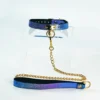 A stunning restraint collar displayed on a clear acrylic stand, featuring a vibrant blue and purple gradient with a textured snakeskin pattern. The collar is made of high-quality leather, secured with a gold metal buckle and a central D-ring. Attached to the D-ring is a sleek gold chain that connects to a matching leash, enhancing the overall aesthetic. This elegant piece of restraint collar gear combines sophistication with playful elements, perfect for those looking to explore intimate and adventurous experiences in style.